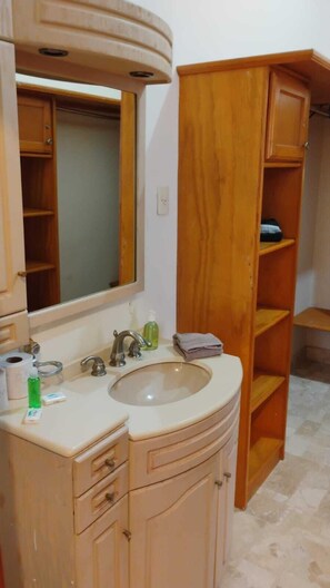 Bathroom with a single sink, vanity, and storage shelving.