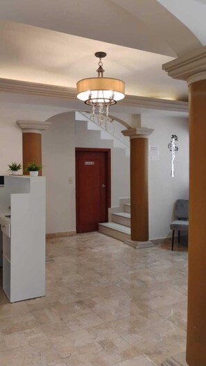 Experience a sophisticated atmosphere with a grand chandelier, marble stairs, and a minimalist reception desk.