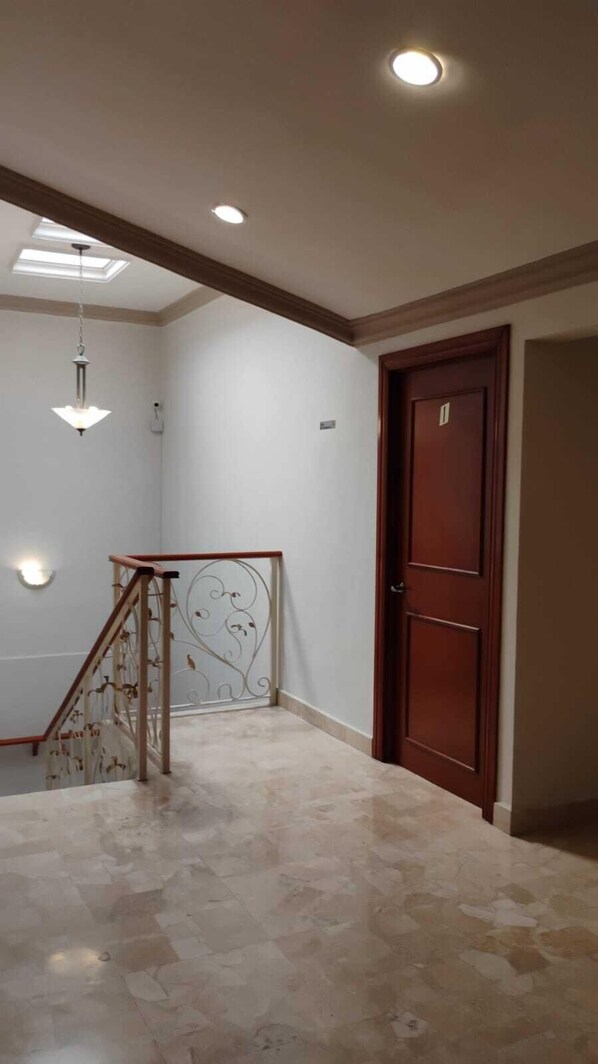 Stunning hallway with a marble floor, wooden door, and staircase with metal railing.