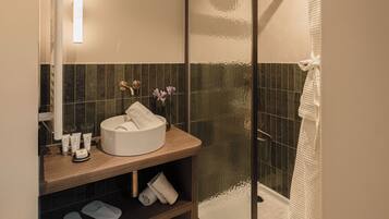 A modern bathroom with a glass-enclosed shower, a round sink, and a wooden vanity.