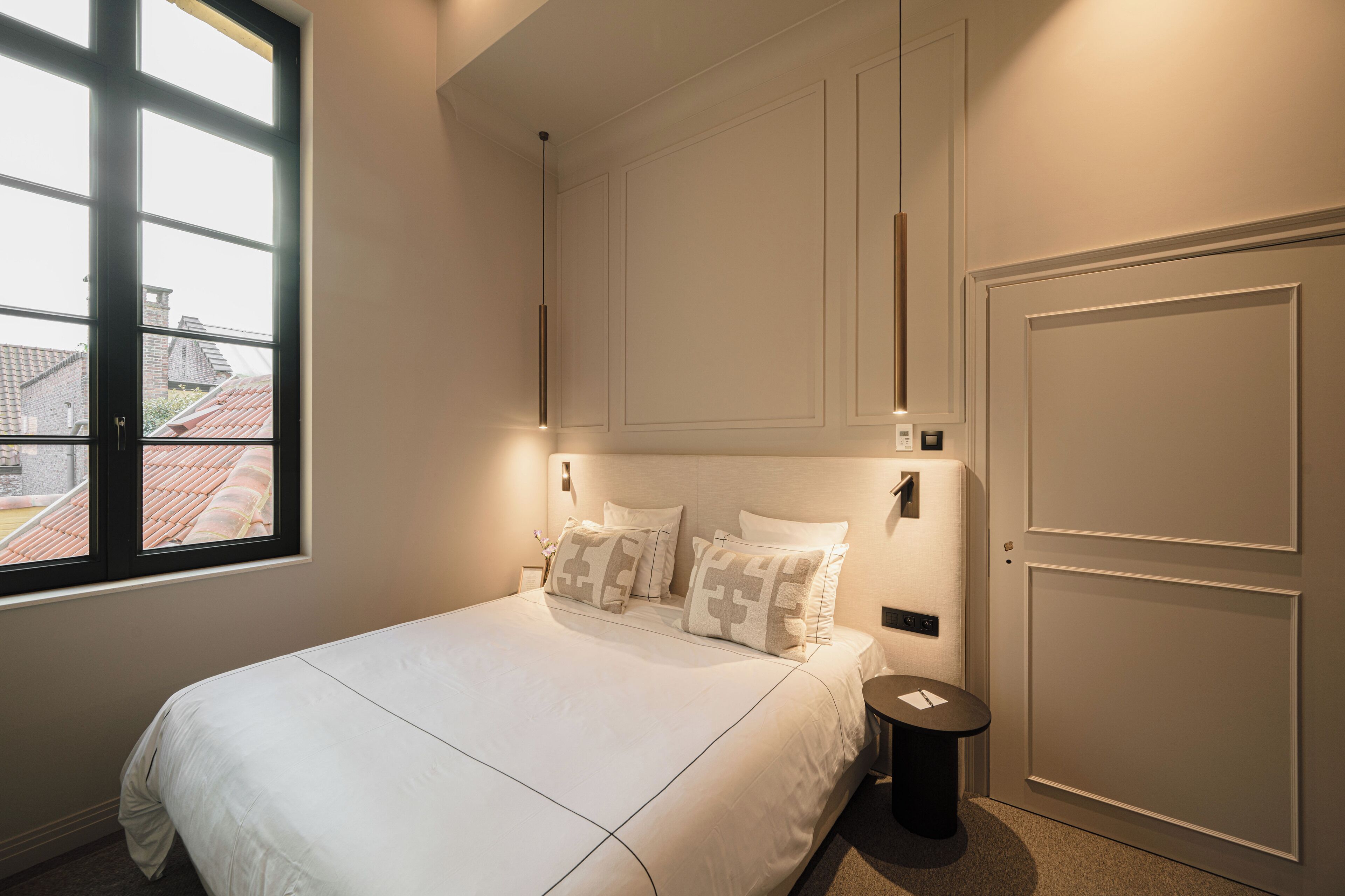 Une chambre à coucher avec un grand lit, une table de chevet, une fenêtre et une porte.