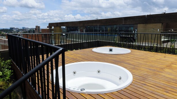 A rooftop deck with two hot tubs and a modern building in the background. - New y modern apto In Virrey (Bogotá)