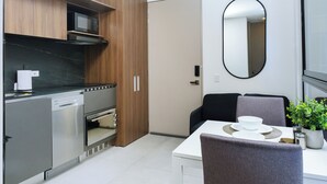 A modern kitchen with stainless steel appliances, wooden cabinets, and a dining area with a white table and chairs. - New y modern apto In Virrey (Bogotá)