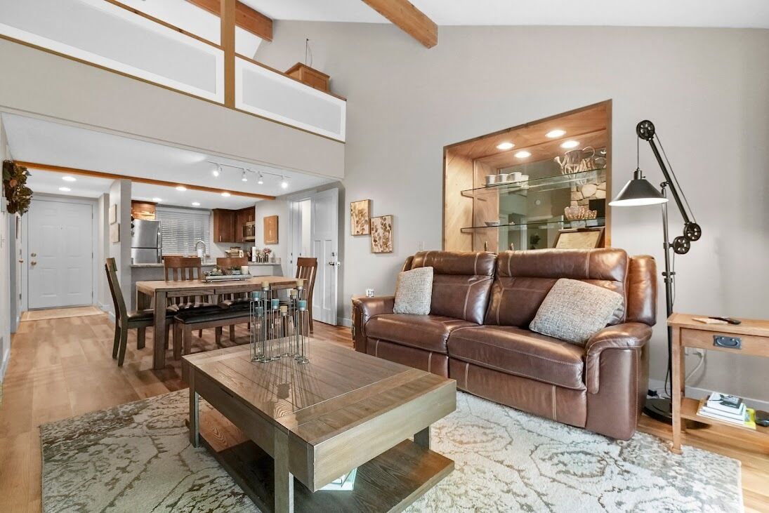 A modern living room with a leather sofa, a wooden coffee table, and a dining area with a table and chairs.