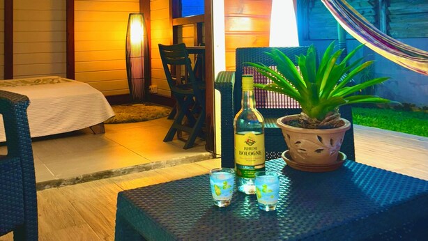 A cozy room with a bed, a table with drinks, a lamp, and a hammock.