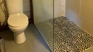 A bathroom with a toilet, a shower enclosure, and tiled walls.