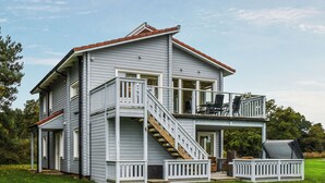 A two-story house with a balcony, a staircase, and outdoor furniture.
