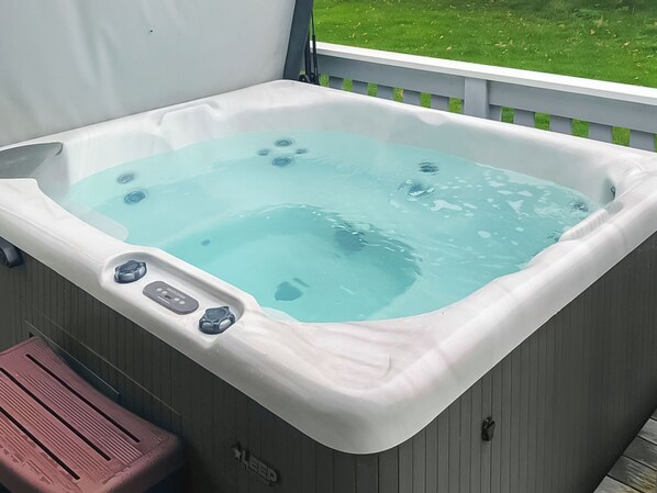 A hot tub with jets, a control panel, and a wooden deck.