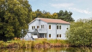 A two-story house with a balcony, situated next to a body of water.