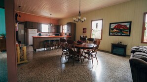 A spacious kitchen with wooden cabinets, a central island, and a dining area with a table and chairs. - Antique Mountain Cabin (Ponce)