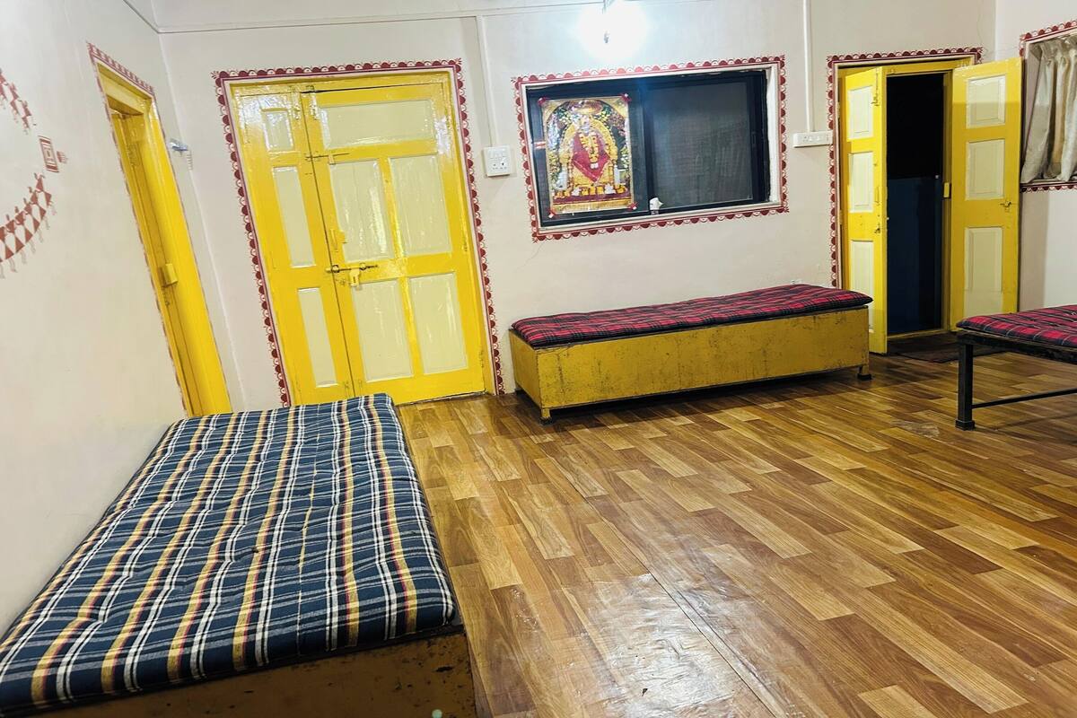 A room with wooden flooring, a bench, and two yellow doors.