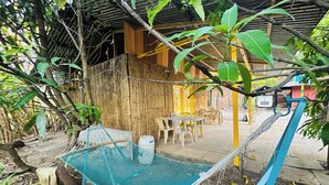 A hammock under a bamboo structure, a wooden door, and a table with chairs outside. - Rajgad Farms & Agritourism (Pune)