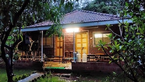 A rustic house with a tiled roof, a brick exterior, and a wooden porch. - Rajgad Farms & Agritourism (Pune)