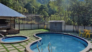 A backyard with a swimming pool, a covered barbecue area, and a fenced yard. - Rajgad Farms & Agritourism (Pune)