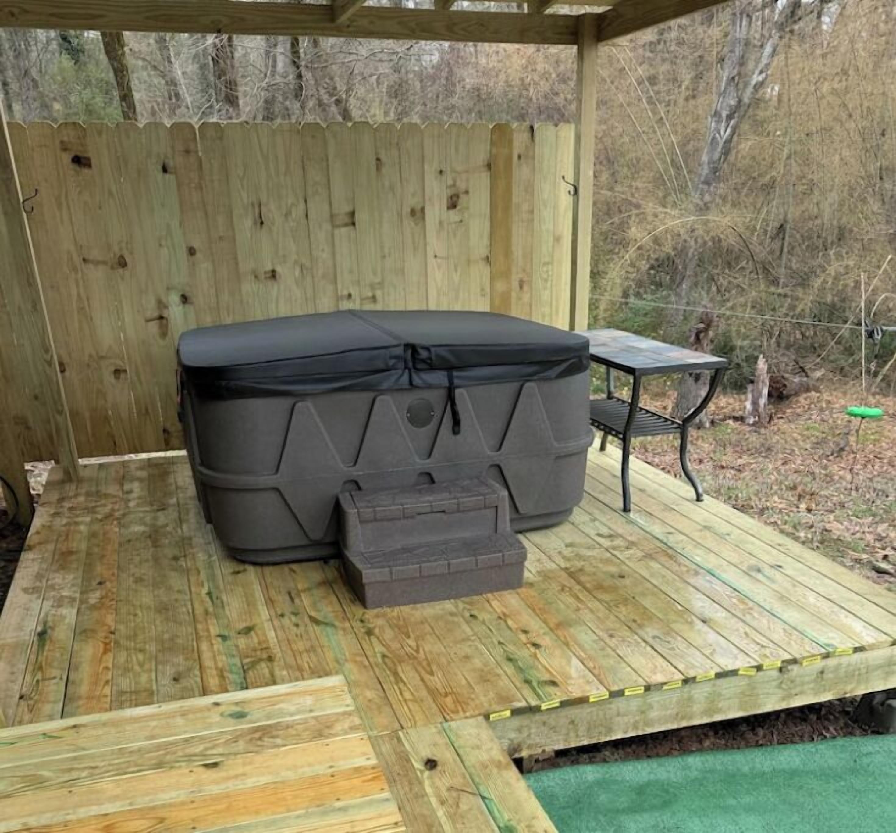 A hot tub on a wooden deck with a wooden fence in the background.