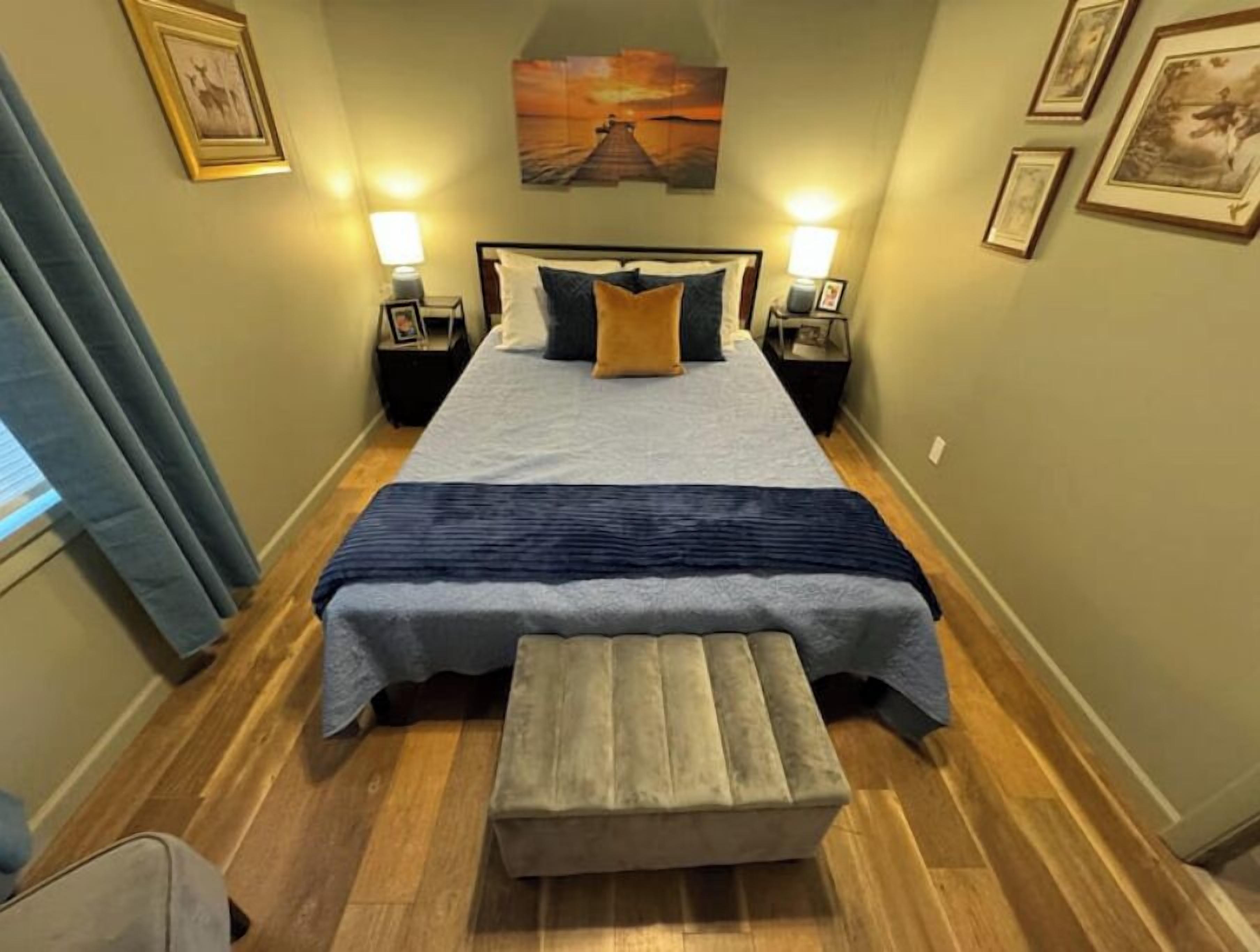 Ein Hotelzimmer mit Bett, Nachttischen, einer Bank und Kunstwerken an den Wänden.
