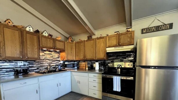 A kitchen with wooden cabinets, a stainless steel refrigerator, and a microwave.