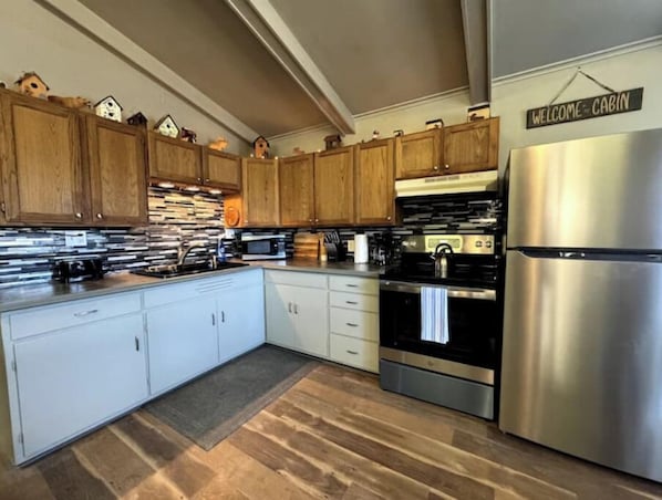 A kitchen with wooden cabinets, a stainless steel refrigerator, and a microwave.
