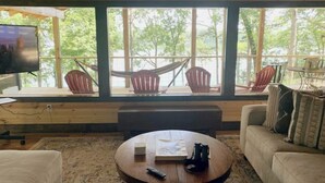 A cozy room with a large window, a round wooden coffee table, a sofa, and two rocking chairs.