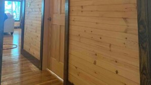 A wooden-paneled hallway with a door and a hanging light fixture.