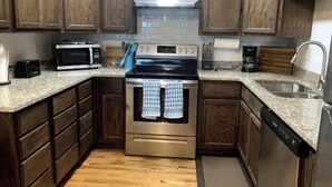 A kitchen with wooden cabinets, a stainless steel stove, a microwave, and a dishwasher.
