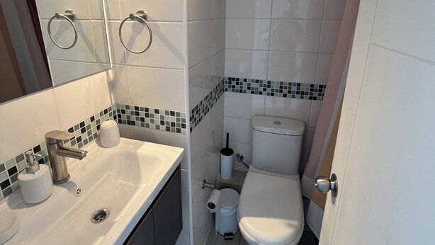 Un baño moderno con lavamanos blanco, inodoro y zona de ducha.