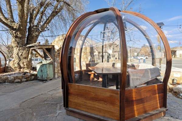 Una estructura en forma de cúpula de madera con una mesa y bancos en su interior.