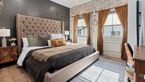 Een slaapkamer met een groot bed, een houten nachtkastje, een bureau en een raam met gordijnen.