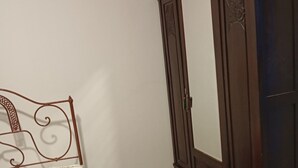 Un dormitorio con cama, armario y espejo.