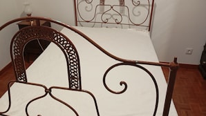 Una cama con estructura metálica y un cabecero decorativo.