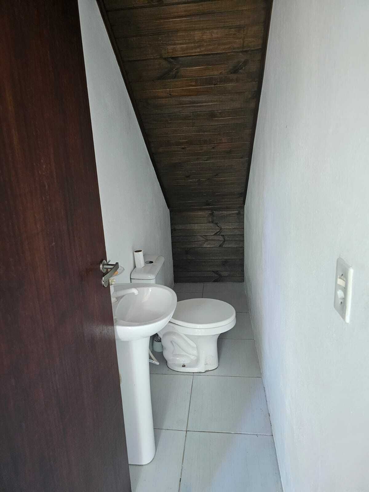 A small, narrow bathroom with a wooden ceiling, white fixtures, and a tiled floor.