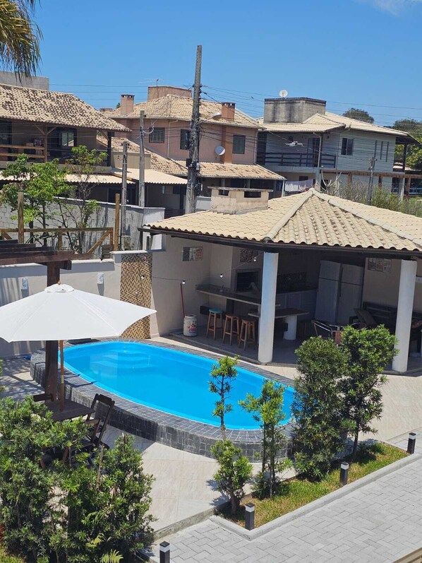 A residential area with a swimming pool, a covered patio, and a view of neighboring houses.