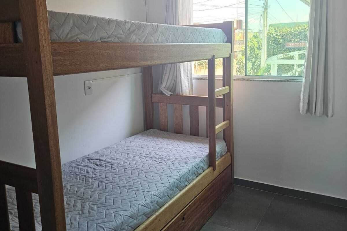 A bunk bed in a room with a window, an air conditioning unit, and a tiled floor.