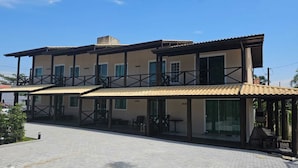 Ein zweistöckiges Gebäude mit einem Balkon, großen Fenstern und einem gepflasterten Innenhof.