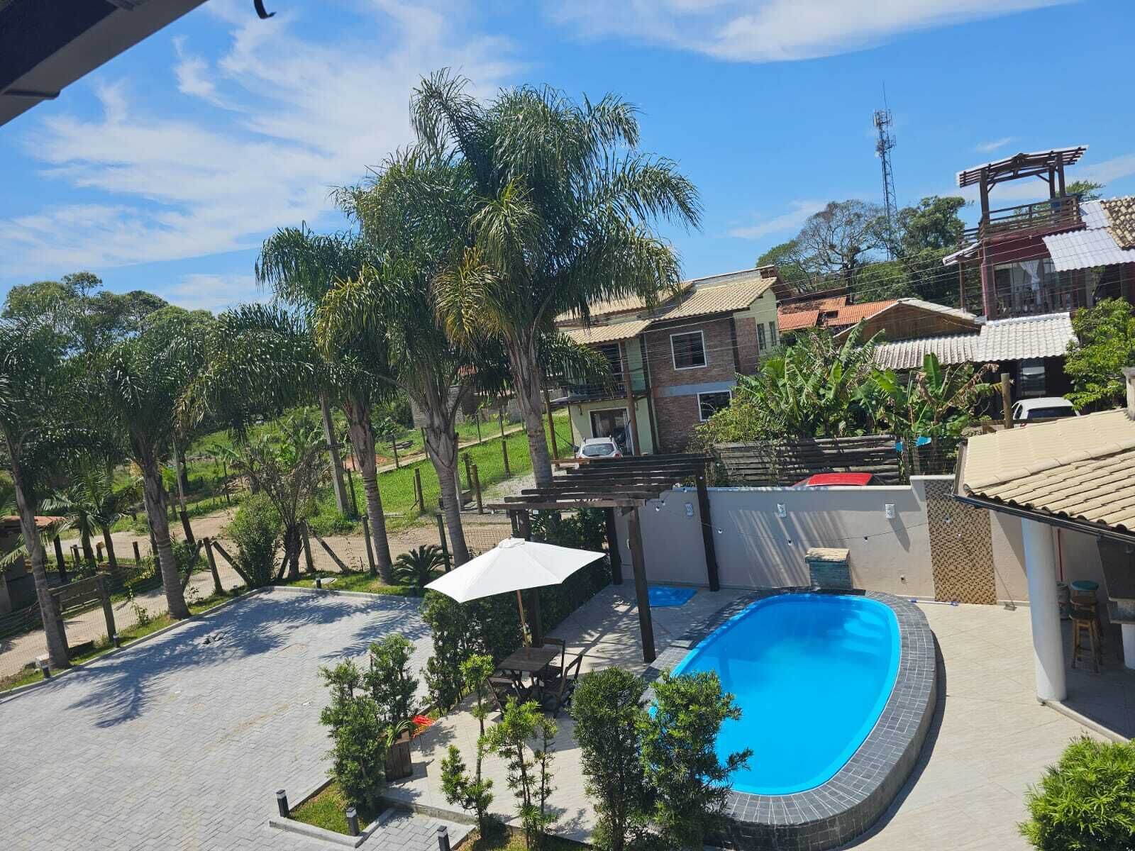 A residential area with a swimming pool, a covered patio, and a view of neighboring houses.