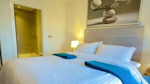 A hotel room with a large bed, a shower, a nightstand with a lamp, and a wall-mounted artwork. - The Mirrored House (Whole Flat) (Darford)