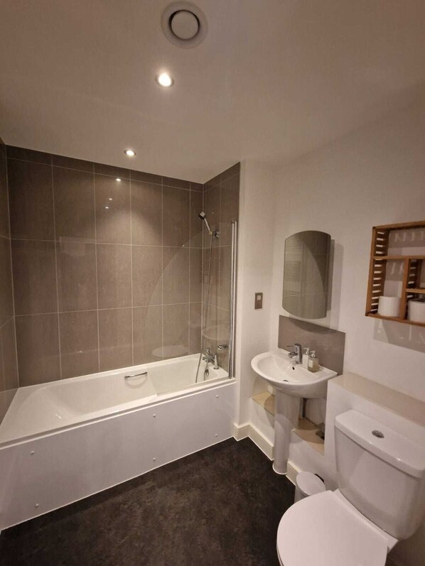 Ein modernes Badezimmer mit einer Glasdusche, einer freistehenden Badewanne, einem Standwaschbecken und einer Toilette.
