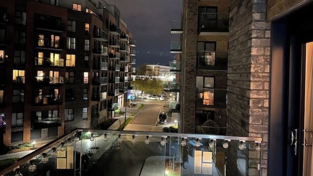 A nighttime view of a multi-story residential building with balconies and windows illuminated. - The Mirrored House (Whole Flat) (Darford)