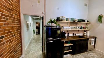 A compact kitchen with a refrigerator, stove, and shelves.