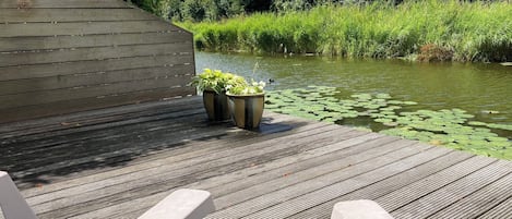 Eine Holzterrasse mit zwei Pflanzkübeln und einer Sitzbank.