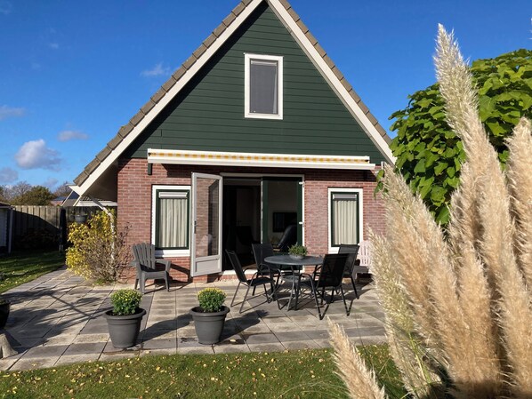 A house with a green roof, a brick facade, and a patio with outdoor furniture.
