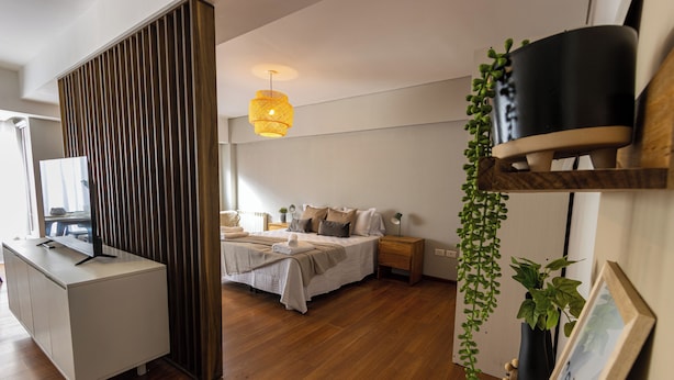 A modern bedroom with a bed, bedside tables, a desk, and a hanging plant.