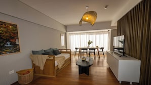 A modern living room with a sofa, dining table, and TV stand.