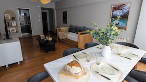 A modern living room with a dining area, wooden furniture, and a large window with a view.