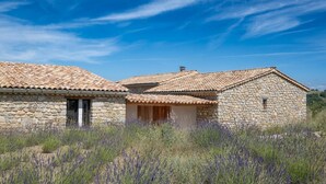 A stone building with a tiled roof, surrounded by tall grass and lavender. - Holiday Home "Time-out" with Mountain Views, Shared Pool, and Wi-Fi (Laragne-Montéglin)