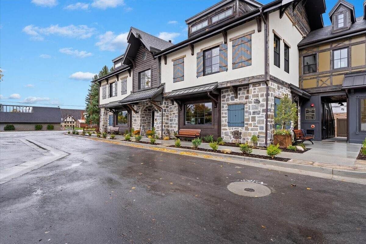 A two-story building with a stone facade, multiple windows, and a covered porch area.