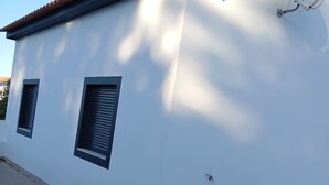A modern building with a white facade, two windows with shutters, and a satellite dish labeled "meo" on the roof. - Casa da Avó Bia (Penhascoso)