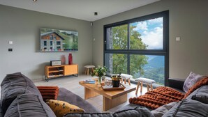 A modern living room with a large window, a wooden coffee table, and a grey sofa.