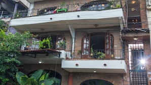 Un immeuble à plusieurs étages doté de balcons, d’une façade en briques et d’une entrée fermée par un portail.