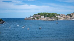 Un pueblo costero con un faro, barcos y edificios a lo largo de la costa.